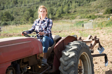 Smiling female farmer working on farm tractor in her smallholding.