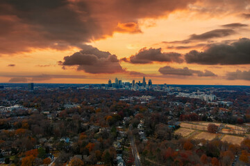 a gorgeous aerial shot of the downtown cityscape with skyscrapers and vast miles of autumn colored trees with red sky and powerful clouds at Freedom Park in Charlotte North Carolina USA