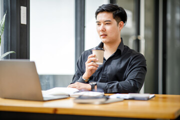 Asian Handsome young smiling businessman working with documents in the office