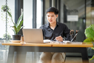 Fototapeta na wymiar Asian Handsome young smiling businessman working with documents in the office