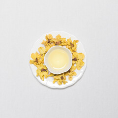 a cup of flower tea with dried flower tea leaves around