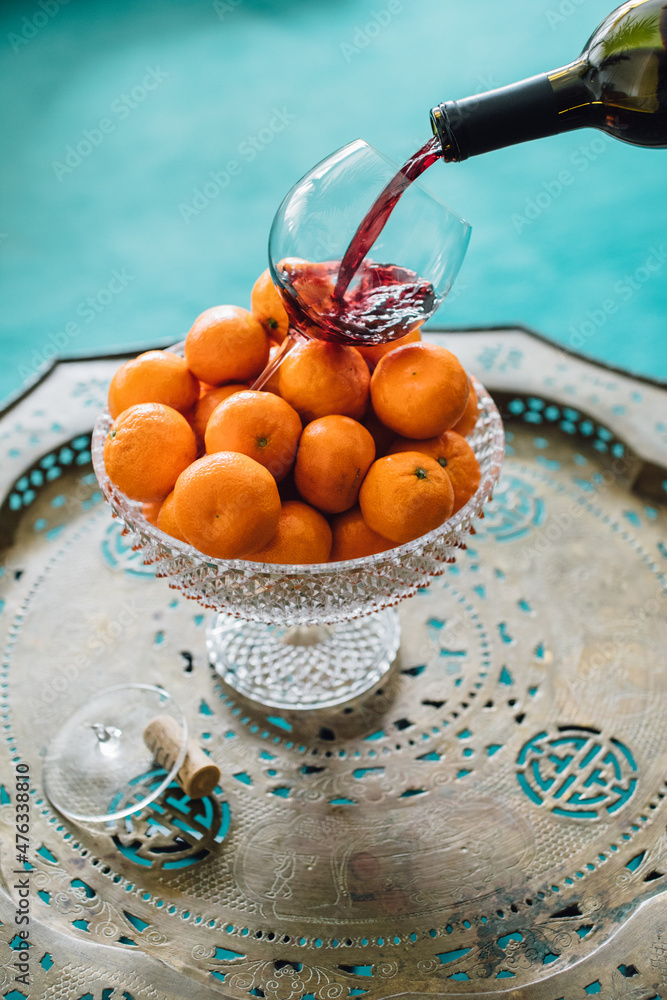 Wall mural whimsical fruity red wine pour into broken glass sitting in crystal bowl of mandarin oranges with te