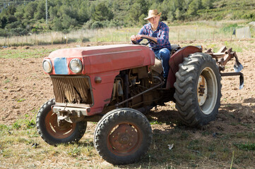 Obraz premium Positive man working on farm tractor. High quality photo