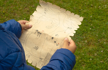 A child is holding an old pirate card in his hands. Children's quest. Pirate treasures.active outdoor games.