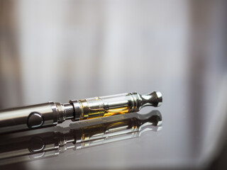 close up shot of cannabis oil in te cartridge on vape pen or call e-marijuana with reflection on...