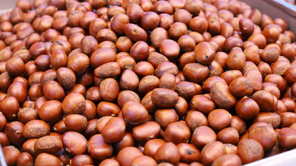 Pile chestnuts on a tray. Background of roasted and cooked Chinese chestnuts ready for sale in the local market. Selective focus