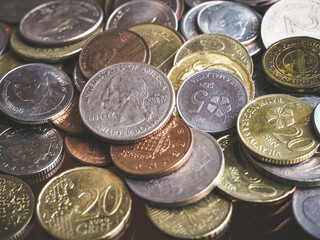 Close up shot of various currency coins with light faded and dark tone with contrast, focus on dollar coin