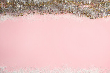 Shiny tinsel and snow on pink background, top view. Space for text