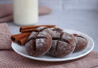 homemade round gingerbread with cinnamon in powdered sugar on a saucer with milk