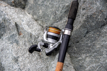 close-up spinning rod for fishing on the background of the stone. Fishing rod and spinning reel for...