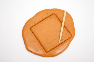 Korean Dalgona sugar candy cookie with a metal needle