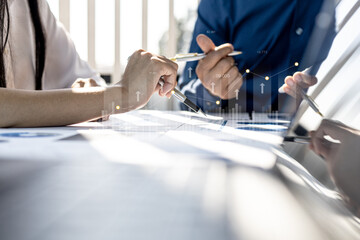 Two businessmen are meeting together, they point to financial documents to discuss plans and solutions, chart graphics showing financial status and performance. Business administration concept.