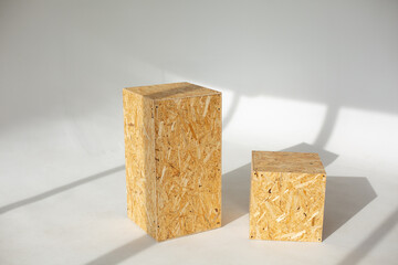 Geometric shapes from pressed OSB wood on a white background in sunlight with shadows. Rectangular and square shape made of wood panels.