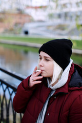 Young thoughtful hipster millennial woman smoking a cigarette outdoors