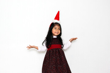 Little brunette Latina girl in red party dress and Christmas hat excited and happy for the arrival of December and celebrate Christmas and New Years
