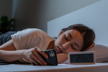 Worried, stressed asian young woman, girl using mobile, smartphone for chatting social media in internet. Insomnia, awake in the night in bedroom, tired and exhausted. Frustrated people with problem.
