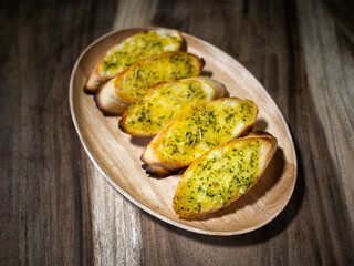 Slices of garlic bread , cheese and herbs on wooden table , top view.
