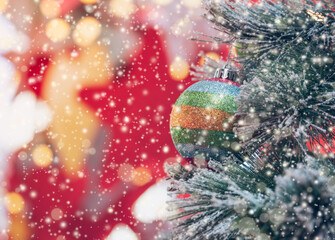 Closeup of festively decorated outdoor colorful ball hanging on Christmas tree with blurred sparkling fairy background. Bokeh garlands in the background. Christmas and New Year concept
