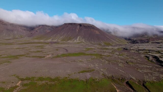 Aerial shot approaching a mountain with fog in Iceland. Barren landscape below, dormant volcano.
