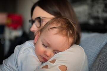 Adorable little boy sleeping on his mother shoulder