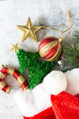 Christmas background in top view with candy cane, pine branch, glitter star, red ornament ball and Santa Claus hat.