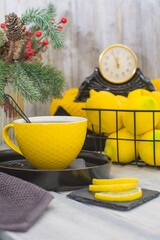 Fototapeta na wymiar A yellow glass of tea on a black porcelain tray. In the background is a black metal basket with lemons.