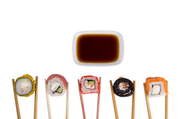 on a white table, an assortment of five Japanese rolls of tuna, salmon, soft cheese, baked in tempura hold wooden sticks, soy sauce on top in a container