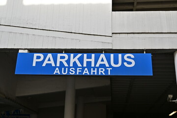 blaues Schild mit der Aufschrift "Parkhaus Ausfahrt" an einer grauen Betonwand