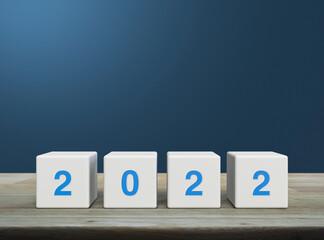 Obraz premium 2022 letter on white block cubes on wooden table over light blue gradient background, Happy new year 2022 cover concept