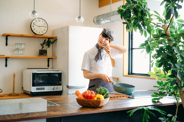 キッチンに立つコックコートを着た調理師（疲労）