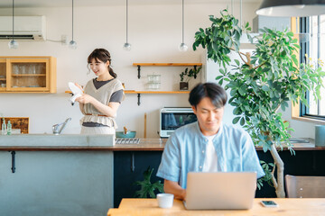 テレワークする男性とキッチンにいる女性（笑顔）
