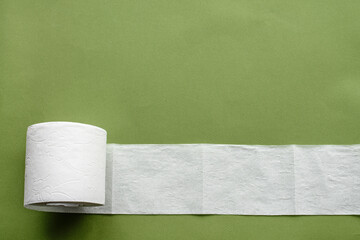 Hygienic flat background on top - toilet paper and a sprig of cotton on a green background