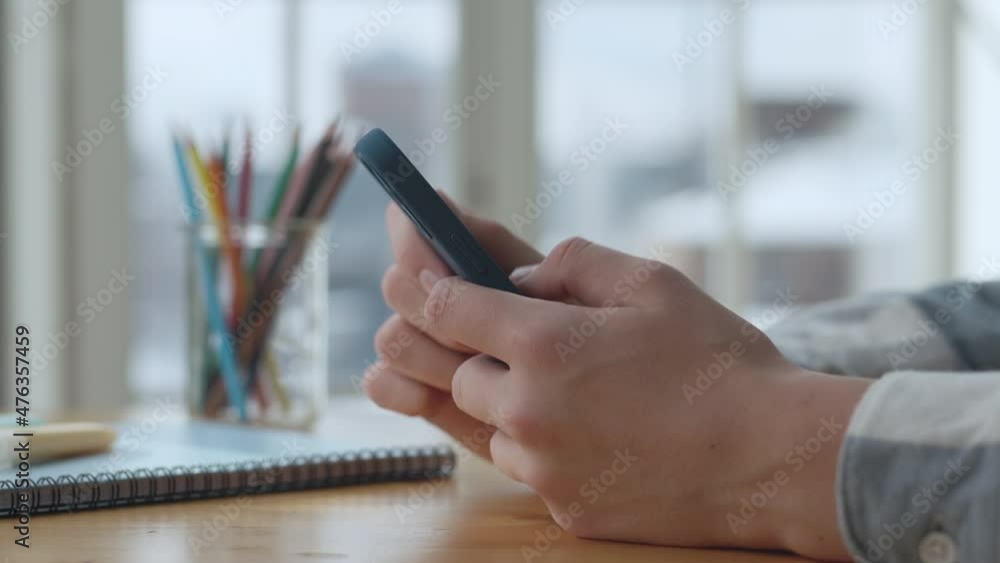 Poster hands man using smart phone in living room at home side view. student typing message on cellphone. c
