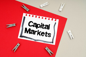 Clothespins and a sheet of notebook with the inscription -Capital Markets