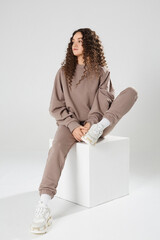 Fashionable young woman in trendy casual sports outfit with stylish hairstyle posing on the white background