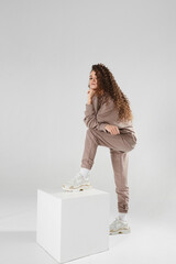 Confident young woman in trendy casual sports outfit with stylish hairstyle standing on the white background