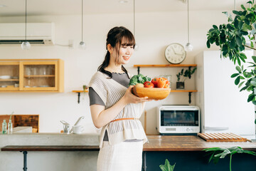 キッチンの前に野菜を持つ女性
