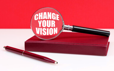 On a white and red background, a notebook, a pen and a magnifying glass, inside which the...