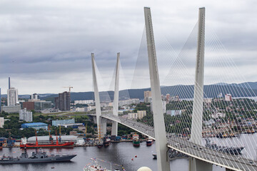 View of Zolotoy Bridge among dark clouds in the city of Vladivostok in cloudy weather. Ships to the...