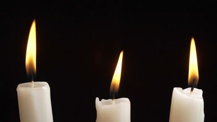 Fototapeta na wymiar Shooting of burning a three candles on dark background
