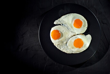 Scrambled eggs in a black plate. Fried eggs on an old concrete table. Copy space and free space for text near food.