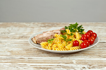 Pasta with meat and tomatoes in a white plate. Pasta on a shabby wooden table.