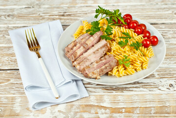 Pasta with meat and tomatoes in a white plate. Pasta on a shabby wooden table.