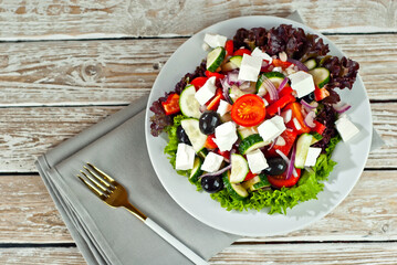 Greek salad on a white background. Salad in a plate on an old wooden table.