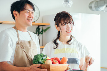 一緒に料理を作る男女（夫婦・フライパンと野菜）
