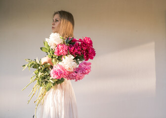 Outdoor portrait of young redhead woman in vintage wedding dress with big bouquet of pink peonies. Woman's Day. Female spring, summer fashion concept. Wedding day. The flowers delivery.Online dating. 