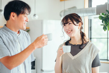 キッチンの前でコーヒーを飲む男女（夫婦）
