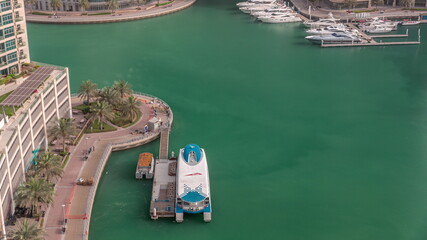 Waterfront promenade with palms in Dubai Marina aerial timelapse.