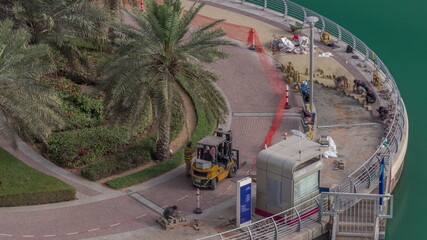 Waterfront promenade with palms in Dubai Marina aerial timelapse.