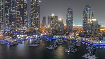 Dubai Marina luxury tourist district with skyscrapers and towers around canal aerial night timelapse